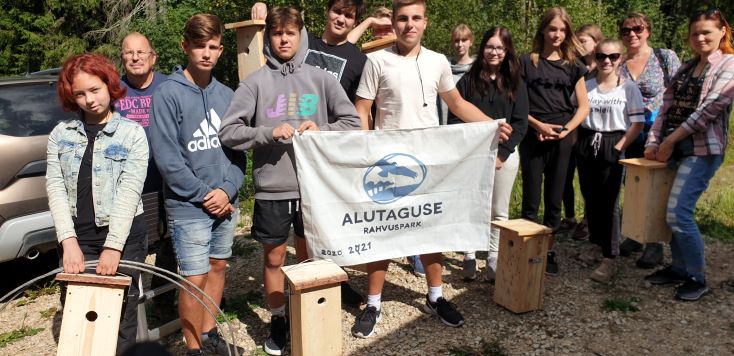 Noored seismas Alutaguse rahvuspargi lipuga metsaserval, käes lendoravale meisterdatud pesitsuskastid.
