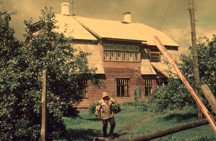 Kollakaspruunide värvidega vanal fotol vana mees korviga maja ees õunapuude vahel 1970ndatel