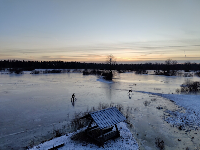 luha peegelsiledal jääl on õhtuvalguses kaks üksikut tõukekelgutajat