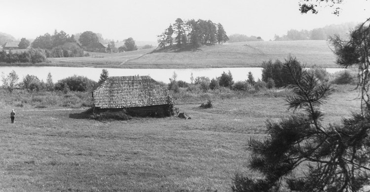 Mustvalgel fotol vana laastukatusega palkhoone järve kaldal