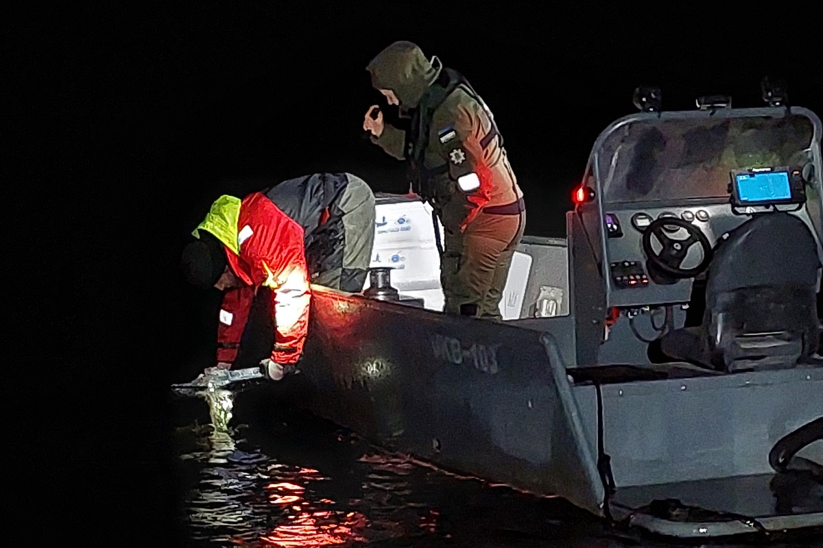 Võrtsjärve lastakse angerjamaimud pimedas mitmest paadist, inspektor näitab paadi ääres tuld