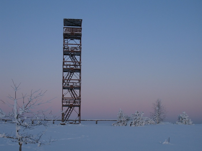 a observation tower with 5 stairs in a snowy landscape with blue-pink colour sky and ground as the sun is setting 