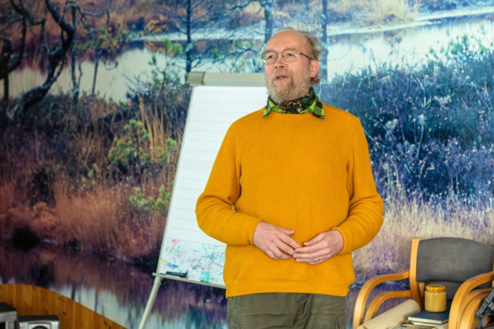 Vana mees kollases kampsunis seismas auditooriumi ees