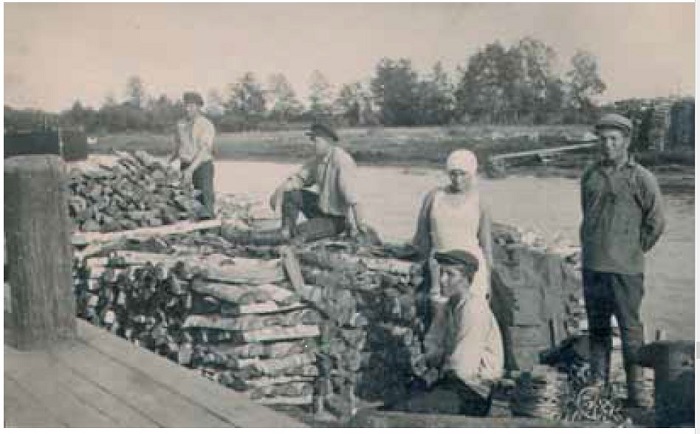 Laiadesse jõepaatidesse laotud suured puuhalud ja noored lodjajuhid Narva jõe ääres