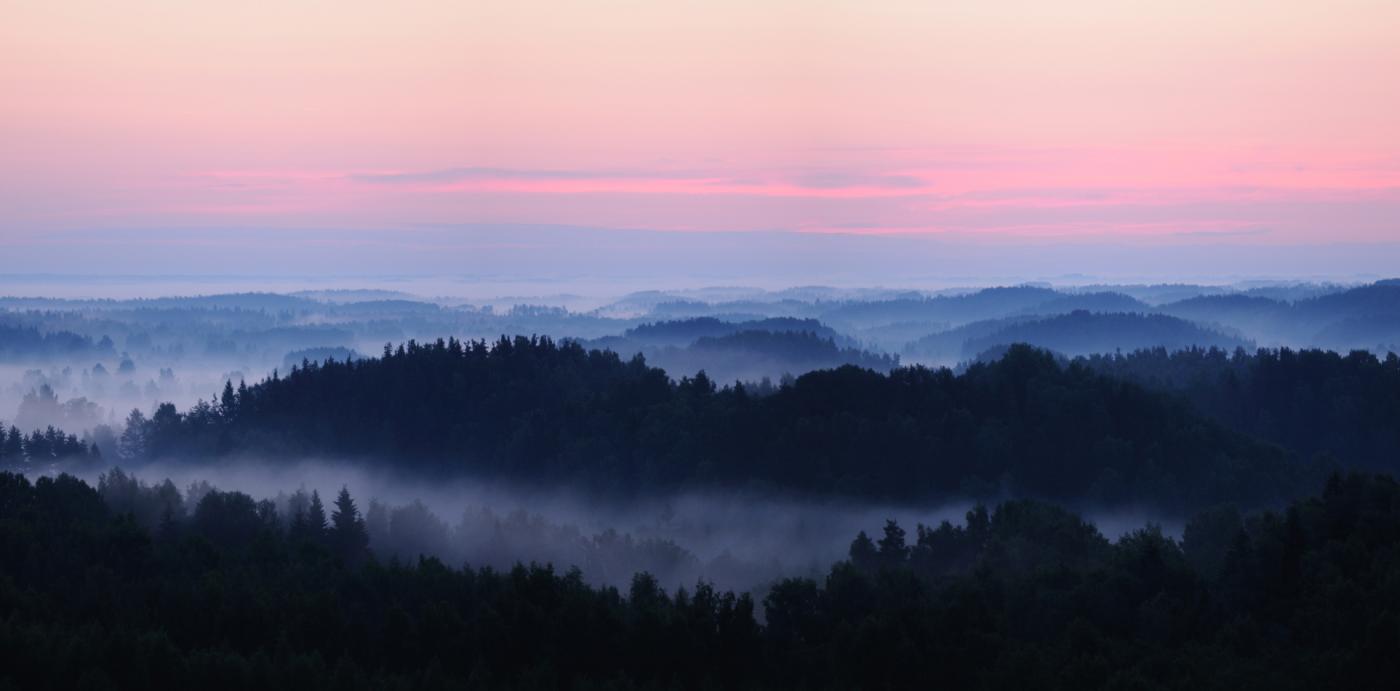 Beautiful terrain of the Karula Uplands with pink sky and foggy hilloks